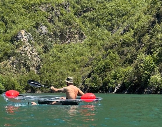 Travelers kayaking in Komani Lake surrounded by mountains